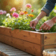 Personne nettoyant une grande jardiniere en bois en terrasse